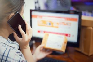 Une femme utilise son téléphone portable après avoir reçu un colis d'achat en ligne. Mise au point sélective